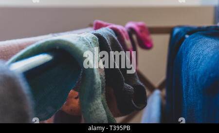 Dunkle, gefiltert, verblasst der ungleichen Paare Socken trocknen auf einem Wäscheständer, hängend Trocknen nach dem Waschen, mit Blue Jeans. Stockfoto