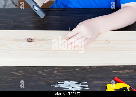 Teil einer Konstruktion Klasse dort, wo ein Kind Hammer Nägel in einem Holzbrett während einer Arbeit Lektion Stockfoto