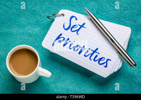 Setzen Sie Prioritäten - Erinnerung an einen Stapel Karteikarten mit einer Tasse Kaffee Stockfoto