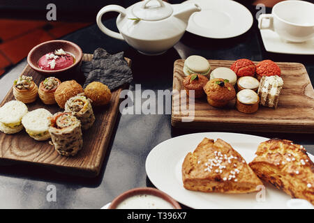 High Tea Brunch mit Gebäck, Muffins, Gebäck und Sandwiches auf eine Tabelle mit heißem Tee in Singapur Stockfoto