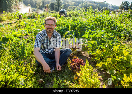 Porträt eines jungen Mannes, die Arbeit in seinem Garten des Grundstückes in einem Gemeinschaftsgarten in Seattle, WA, USA Stockfoto