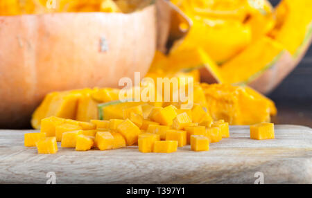 In Scheiben geschnittene und andere Formen der Reife orange Kürbis beim Kochen und Essen, Nahaufnahme in der Küche Stockfoto