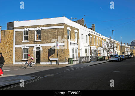 Eine Frau mit dem Fahrrad auf Hargwyne Straße und eine Reihe von Reihenhäusern auf Pulross Straße in Brixton, London SW9 England UK KATHY DEWITT Stockfoto