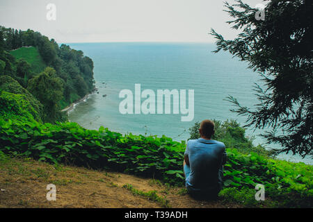 Die Silhouette eines jungen Kerl, der am Rande der Aussichtsplattform befindet sich im Botanischen Garten von Batumi. Stockfoto