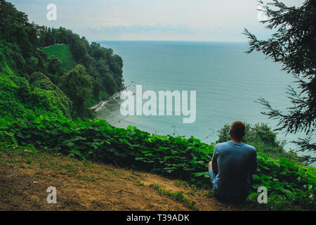 Die Silhouette eines jungen Kerl, der am Rande der Aussichtsplattform befindet sich im Botanischen Garten von Batumi. Stockfoto