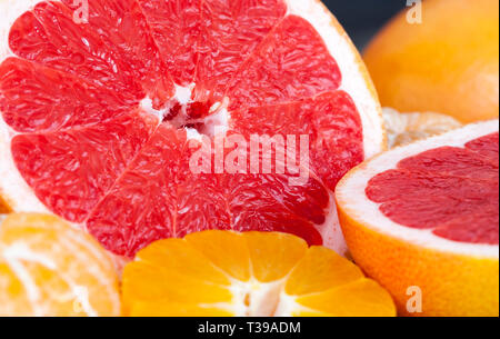 Vorbereitet von Zitrusfrüchten Früchte zu essen, einen kleinen Mandarin Schneiden mit einem Messer in Scheiben schneiden und zusammen mit einem sauren Rote Grapefruit Stockfoto