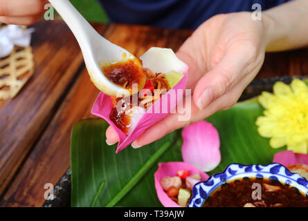 Hand süßen und würzigen Dip in thailändischen Stil frischen Lotus Petal gewickelt Vorspeise Holding in der Hand Stockfoto