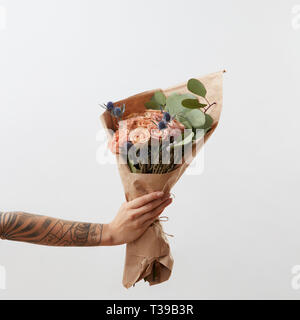 Zarte Blumen lebende Korallen Rosen und eryngium als einen schönen Blumenstrauß in Girl's Hand mit Tattoo, kopieren. Herzlichen Glückwunsch Karte. Stockfoto