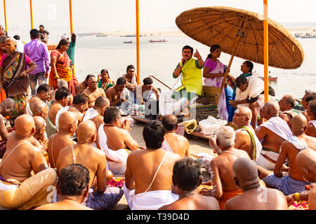 VARANASI, Indien, 10.MÄRZ 2019 - Hinduistische Mönche Verhalten eine Zeremonie, die Morgendämmerung an den Ufern des Ganges zu erfüllen, und die indischen Markierungsfahne anheben Stockfoto