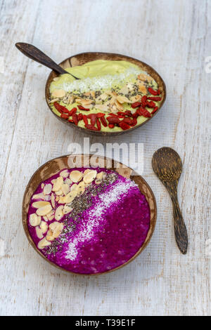 Zwei Smoothie in Kokosnuss Schalen mit Dragon Obst-, Avocado-, Mandel- flocken, coconut Chips, Goji Beeren und Chia Samen zum Frühstück, bis zu schließen. Die Konz Stockfoto