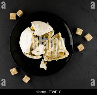 Meringue mit Muttern auf eine schwarze Platte. Makro Modus. Rohrzucker. Süßigkeit. Flach. Stockfoto