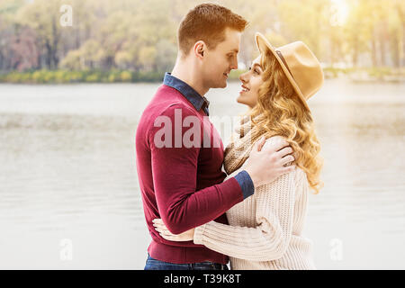 Liebe ist in der Luft. Porträt der jungen umarmen Paar in Freizeitkleidung sich einander und lächelnd, während man im Freien. Schönes Paar in Stockfoto
