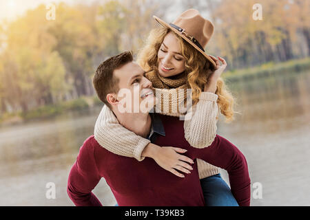 Immer glücklich zusammen. Portrait von stattlichen Mann, der Huckepack Fahrt zu seiner Freundin. Junger Mann, der schöne Frau auf den Schultern. Paar havi Stockfoto