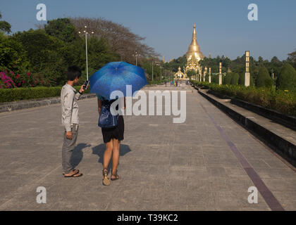 Junge paar hält einen Schirm wandern in Park & der Menschen People's Square, im Hintergrund der Shwedagon Pagode, Yangon, Myanmar (Birma) Stockfoto