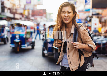 Junge asiatische Frau touristische Frau mit Lächeln zu Fuß und mit Rucksack auf der Khaosan Road in Bangkok, Thailand. Reisen und Rucksack in Asien Konzept Stockfoto