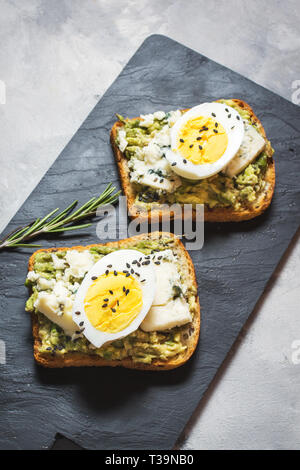 Ei und Avocado Sandwiches mit Frischkäse für gesundes Frühstück auf konkreten Hintergrund Stockfoto