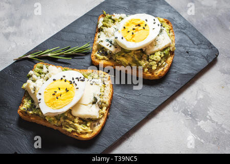 Ei und Avocado Sandwiches mit Frischkäse für gesundes Frühstück auf konkreten Hintergrund Stockfoto