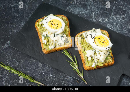 Ei und Avocado Sandwiches mit Frischkäse für gesundes Frühstück auf Stein Hintergrund Stockfoto