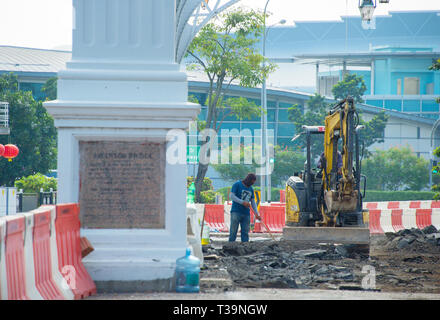 Baustelle Arbeitnehmer durch die Bagger an der Sanierung der Straße Fahrbahn in Singapore Downtown Stockfoto