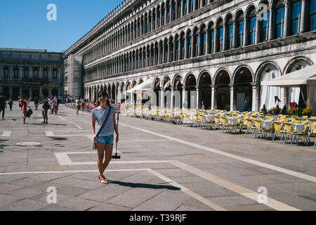 Venedig, Italien - 9 September, 2018: Die junge lächelnde Frau touristische Wandern am St. Mark's Platz, Piazza San Marco mit einem selfie Stick in die Hände. Reisen con Stockfoto