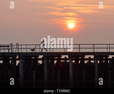 Aberystwyth Wales UK. 07.April 2019. Uk Wetter: Frau läuft mit Hund in während auf dem bootssteg an einem sonnigen Sonntag im Aberystywth, Wales. © rhodri Jones/A Stockfoto