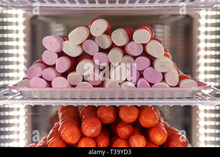 Rosa und weissen Marshmallow und Erdbeeren Spieße in einem Kühlschrank mit LED-Leuchten gestapelt. Querformat. Stockfoto