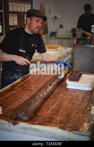 Cambridge, UK - Dezember, 2018. Ein Mann, der in einer Bäckerei Fudge. Fudge ist eine Art von kandiszucker durch Mischen von Zucker, Butter und Milch. Stockfoto