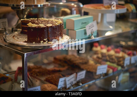 Eine Schokolade und gesalzene Karamell Kuchen in einer Bäckerei mit anderen Kuchen auf einem verschwommenen Hintergrund. Querformat. Stockfoto