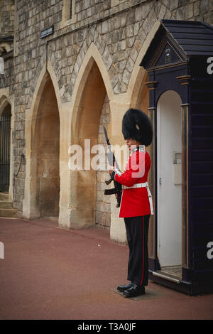 Windsor, Großbritannien - Dezember, 2018. Ein sentry Grenadier guard in seine ikonische einheitliche außerhalb Windsor Castle Gate. Stockfoto