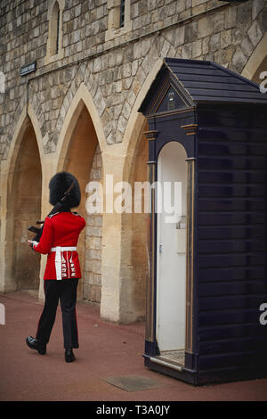 Windsor, Großbritannien - Dezember, 2018. Ein sentry Grenadier guard in seine ikonische einheitliche außerhalb Windsor Castle Gate. Stockfoto