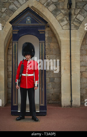 Windsor, Großbritannien - Dezember, 2018. Ein sentry Grenadier guard in seine ikonische einheitliche außerhalb Windsor Castle Gate. Stockfoto