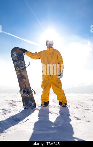 Professionelle Snowboarder stehen mit Snowboard in den Bergen. Schöne Berglandschaft im Hintergrund. Foto auf ein Thema von Extremsport Stockfoto