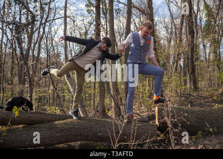 Zwei Männer, ein schwules Paar Hände halten, Wandern in Wäldern, einander helfen, die ein Protokoll. Stockfoto