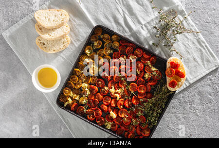 Rote gebackene Kirschtomaten in Backblech auf konkreten Hintergrund der Ansicht von oben Stockfoto