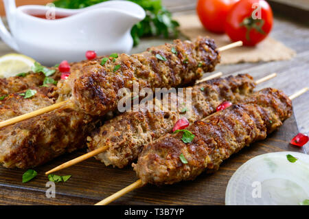 Köstliche lula Kebab auf einem Holztisch. Gehacktes Fleisch auf Holzspieße, gegrillt. Östliche Küche. Stockfoto