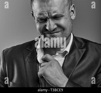 Unglücklich deprimiert Kahlen wütend Geschäftsmann ziehen der Hemdkragen mit sehr schlechten Emotionen in Bürosoftware auf Grau studio Hintergrund. Closeup Portrait. Stockfoto