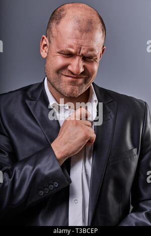 Unglücklich betonte Kahlen wütend Geschäftsmann ziehen der Hemdkragen mit sehr schlechten Emotionen in Bürosoftware auf Grau studio Hintergrund. Closeup Portrait Stockfoto