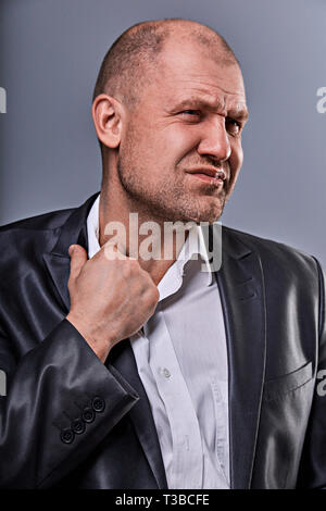 Unglücklich betonte Kahlen wütend Geschäftsmann ziehen der Hemdkragen mit sehr schlechten Emotionen in Bürosoftware auf Grau studio Hintergrund. Closeup Portrait Stockfoto