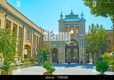 Teheran, Iran - Oktober 25, 2017: Spaziergang entlang der schattigen Straße der Bagh-e Melli Garten mit Blick auf die reich verzierten Sardar-e Bagh-e Melli Tor mit traditio Stockfoto