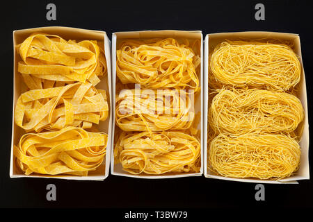 Satz von verschiedenen Teigwaren in Papier Boxen auf schwarzem Hintergrund, Ansicht von oben. Close-up. Stockfoto