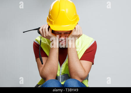 Foto von umgekippt Arbeiter in gelben Helm mit Walkie talkie auf leeren grauen Hintergrund Stockfoto