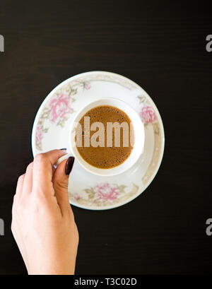 Top die Ansicht von Frau Hand mit der Kaffeetasse auf dem Tisch Stockfoto