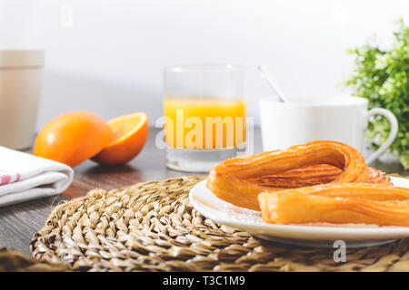 Leckere spanische Churros, Orangensaft, Kaffee Frühstück. Orange in Scheiben geschnitten. Tischplatte mit Churros. Weißer Hintergrund Stockfoto