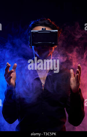 Portrait des jungen Mannes unter Rauch in virtuellen Schutzbrille und spielen in der virtuellen Realität Spiel Stockfoto