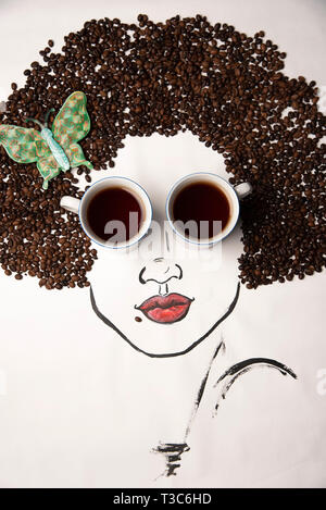 Konzeptuelle Fotografie. Die bemalten Gesicht des Mädchens, von Tassen Kaffee statt Brille ergänzt, und Haare aus Kaffeebohnen Stockfoto