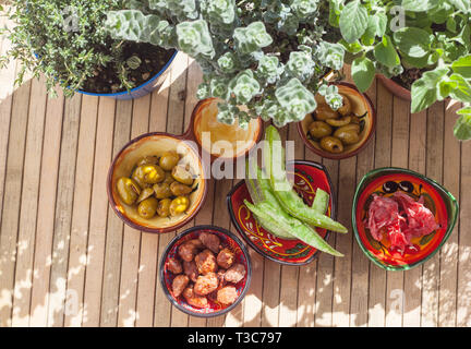 TopView von Grapefruit und kandierten Hibiskus Blumen, würzige Oliven, karamellisierten Mandeln und aromatischen Pflanzen in der Licht und Schatten. Andalusische Pro Stockfoto