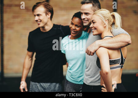 Vielfältige Gruppe von lächelnden Freunde in Sportkleidung ständigen Arm in Arm in einer Turnhalle nach dem Training Klasse zusammen Stockfoto