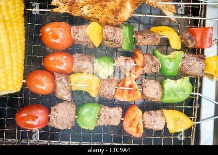 Fleischstücke und Gemüse auf Spieße auf Grill, Ansicht von oben Stockfoto