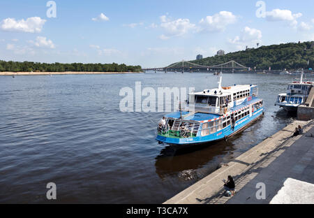 Boot im City Wharf des Dnjepr in Kiew vor dem Hintergrund einer Brücke über den Fluss und die städtischen bewaldeten Park Pisten günstig Stockfoto