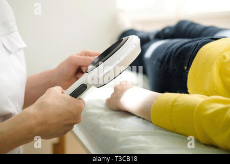 Dermatologe mit einem professionellen Lupe beim Tun der Haut Untersuchung, Kontrolle gutartige Muttermale auf der Hand. Hautarzt untersuchen Muttermal ein Stockfoto